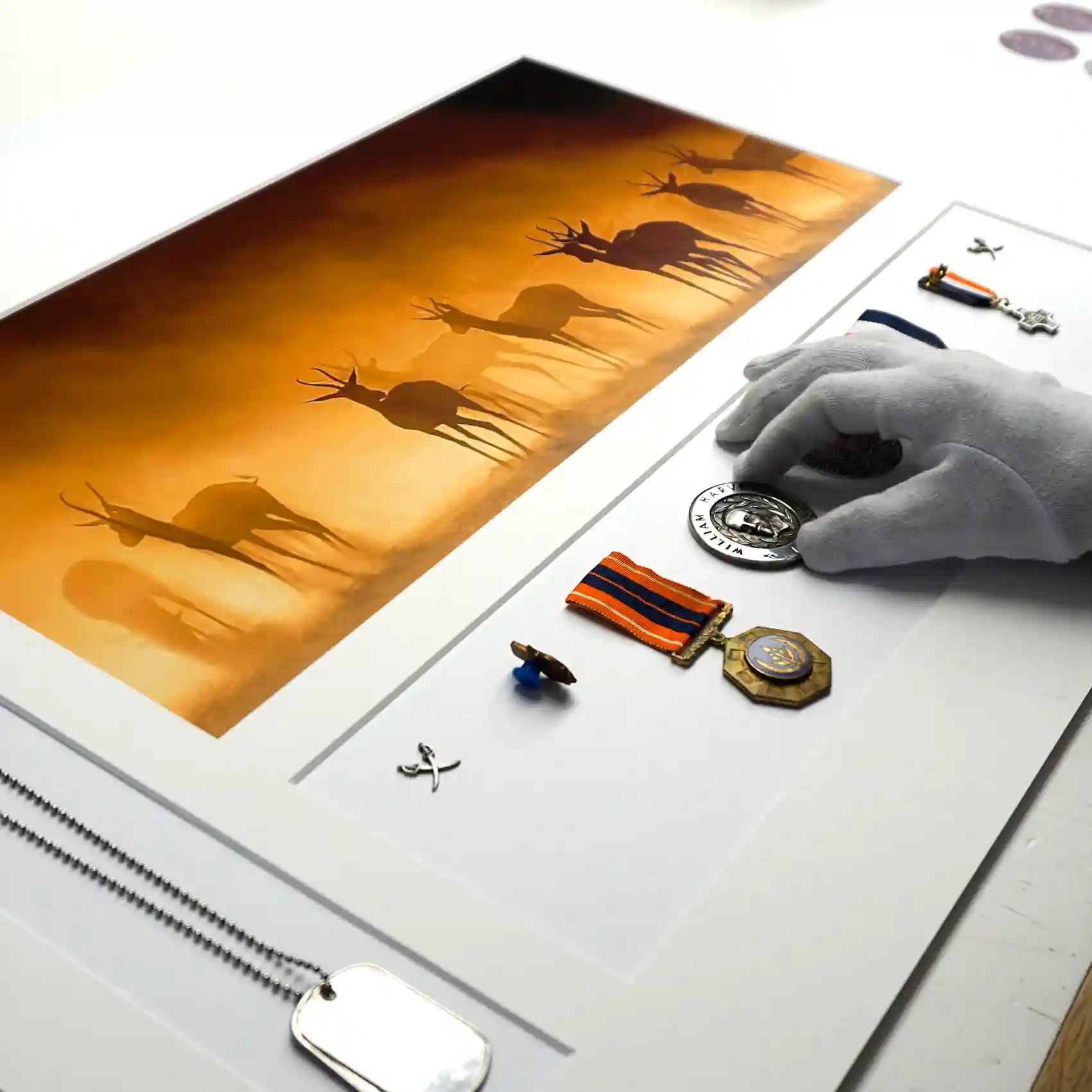 Framing conservator arranging military medals and memorabilia alongside a wildlife photograph on a precision-cut conservation mount during the bespoke memorabilia framing process.