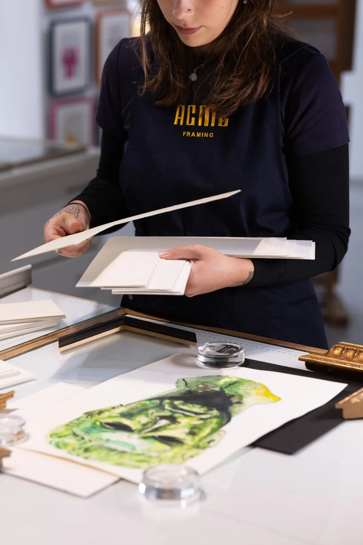 ACME Framing designer selecting archival matboard samples during a bespoke picture framing consultation for original artwork in the Sydney workshop.