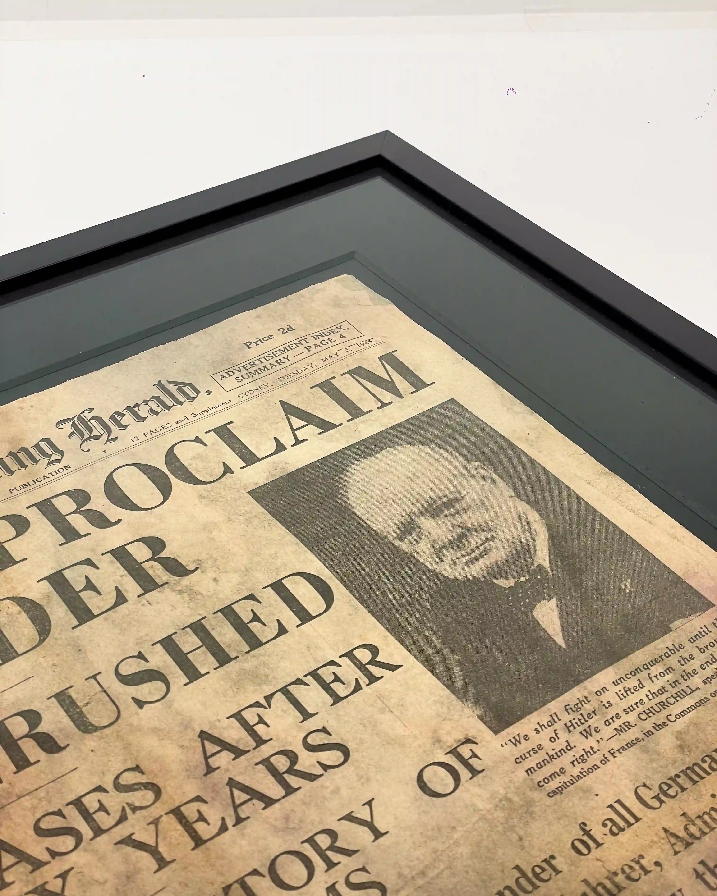 Close-up of a handcrafted black shadow box frame displaying a vintage newspaper front page with a deep charcoal mat, showcasing museum-style presentation, clean mitred corners and bespoke framing craftsmanship.