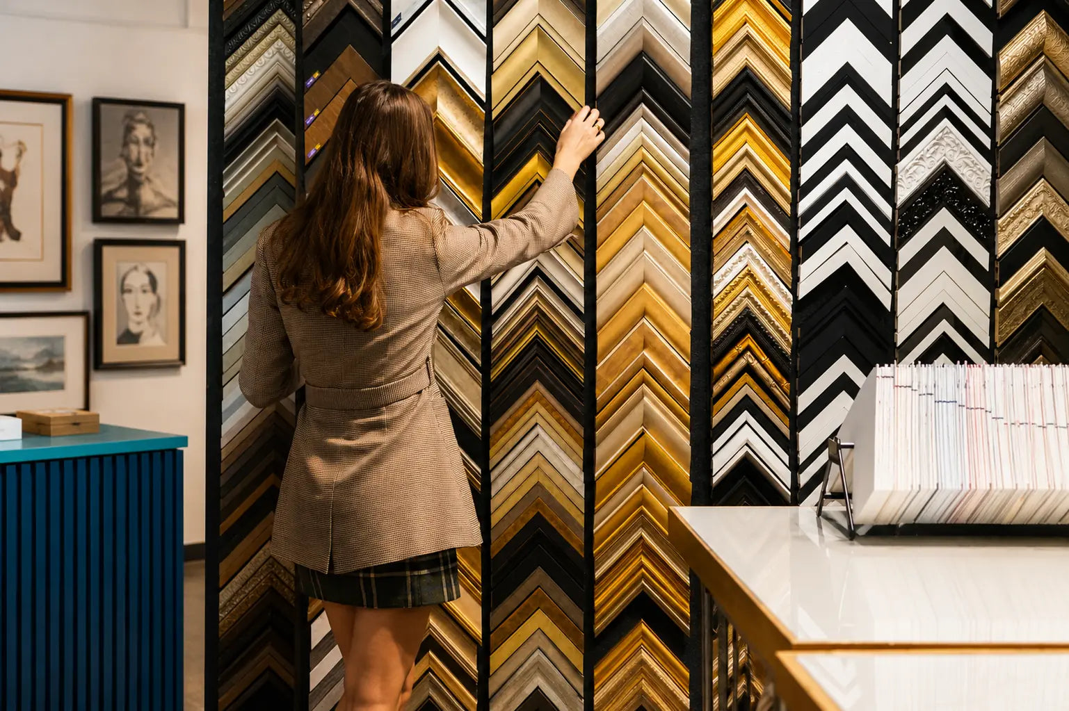 Customer exploring a wide selection of bespoke picture frame mouldings during a custom framing consultation in a picture framing studio.