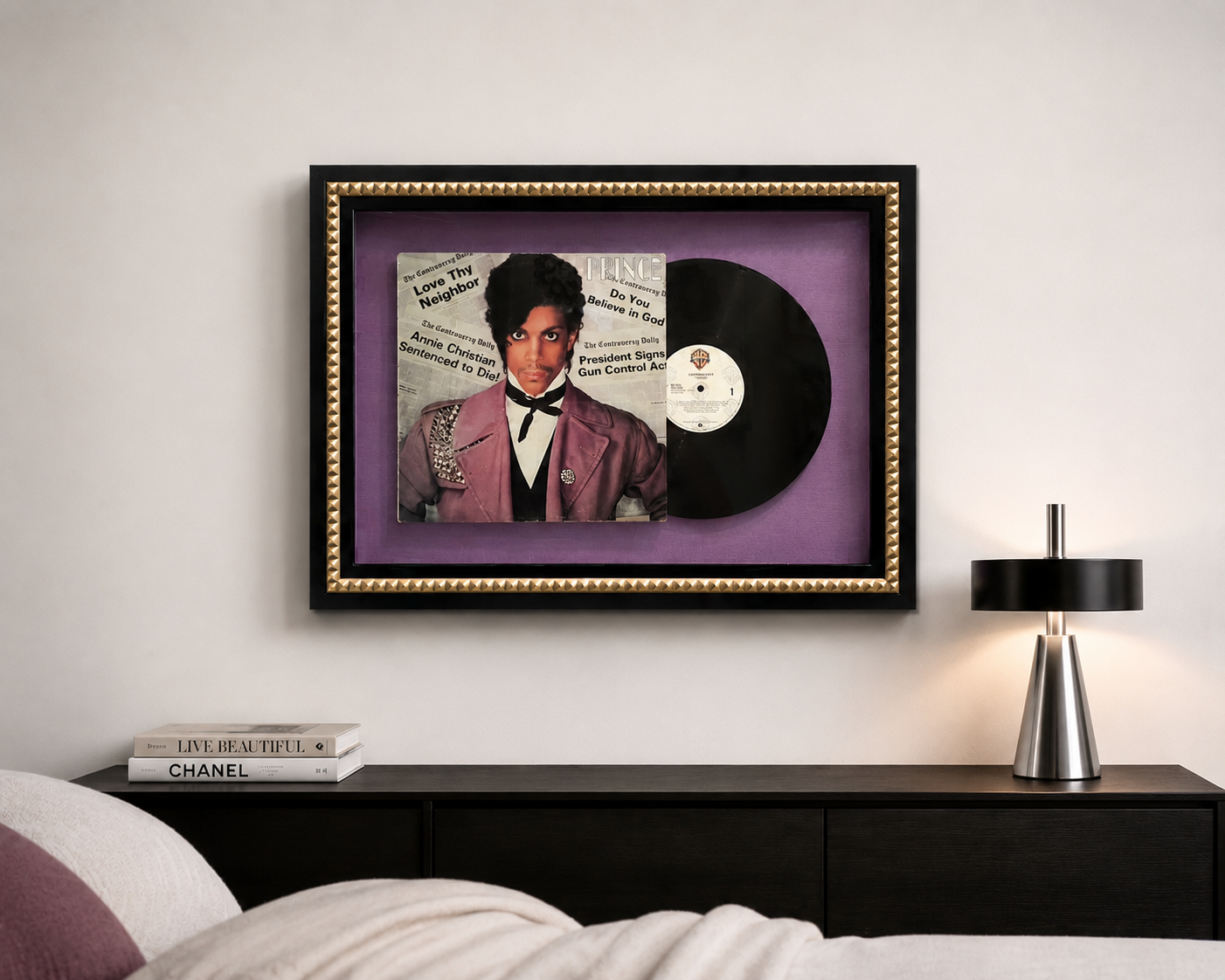 Custom framed Prince "Controversy" vinyl record and album cover displayed above a black console in a contemporary bedroom, showcasing bespoke memorabilia framing.